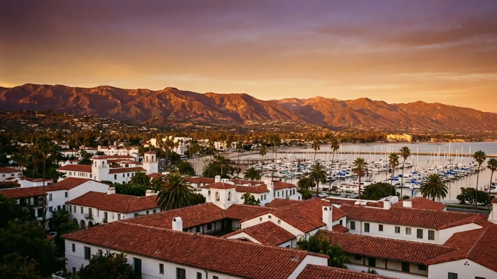 Sunset landscape of Santa Barbara featuring Spanish architecture, harbor, and mountains.